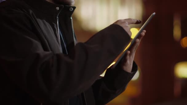 Guy surft im Freien mit dem Tablet im Internet. Mann händigt Tablet auf Straße aus. — Stockvideo