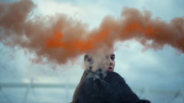 Tyttö heiluttaa kättään kameralle savupommilla. Nuori nainen poseeraa kameran edessä — kuvapankkivalokuva