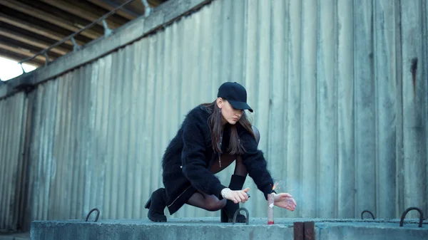 Girl lighting smoke grenade on street. Lady holding sparkling smoke bomb in hand