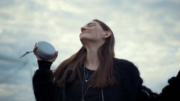 Flicka dansar på stadens gata. Leende kvinna lyssnar musik på trådlös högtalare — Stockvideo