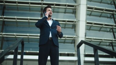 Stadyumun yanında duran yakın çekim adamı. İş adamı sokakta akıllı telefondan konuşuyor.