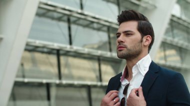 Portrait man looking away at street. Businessman checking time on watch outdoors