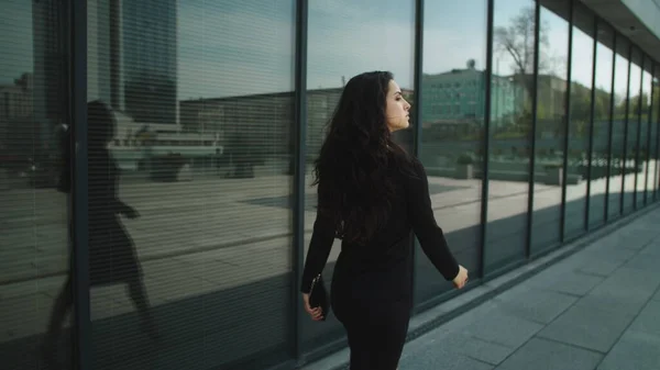 Vista posterior mujer emprendedora tocando el cabello. Mujer caminando en vestido en la calle — Foto de Stock