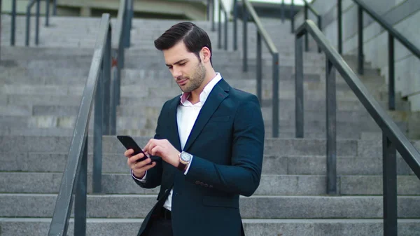 Closeup businessman laughing at street. Man using modern smartphone outside — Stockfoto