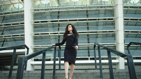 Mujer bajando con vestido negro afuera. Mujer sexy tocando el pelo —  Fotos de Stock