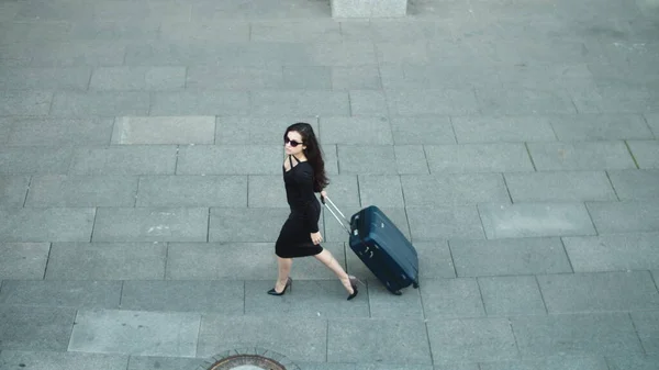 Mujer vista lateral caminando con maleta. Mujer mirando hacia otro lado en vestido en la calle —  Fotos de Stock