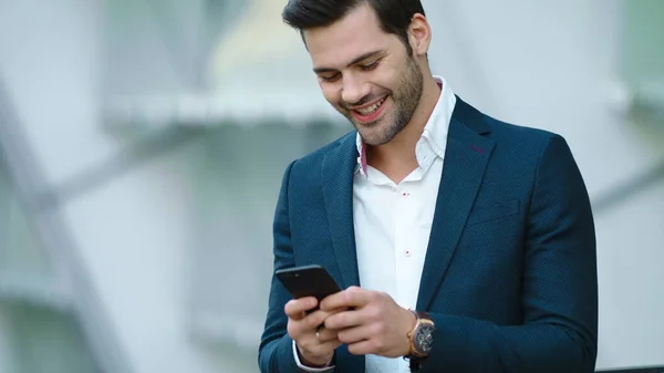 Homem de negócios retrato usando smartphone. Homem sorrindo com telefone na mão ao ar livre — Fotografia de Stock