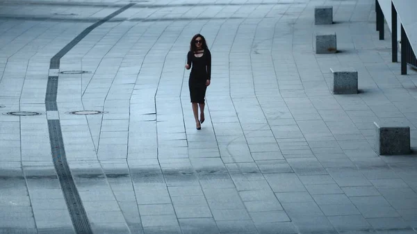 Mujer caminando en cámara lenta en la acera. Mujer quitándose gafas de sol en la calle —  Fotos de Stock