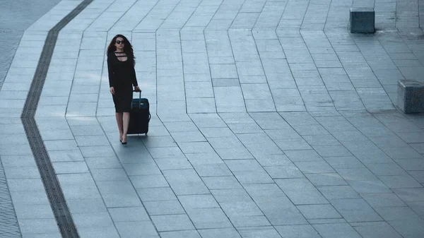 Γυναίκα περπατά με αποσκευές στο δρόμο. Γυναίκα κοιτάζει μακριά με τη βαλίτσα στο δρόμο — Φωτογραφία Αρχείου