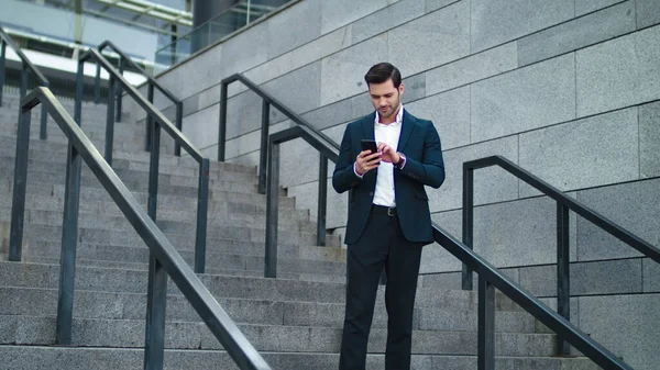 Businessman smiling with phone in hand at street. Man using phone in suit — Stock Photo, Image