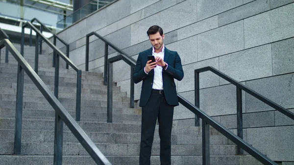 Biznesmen korzystający z telefonu na schodach. Biznesmen uśmiechający się na schodach — Zdjęcie stockowe