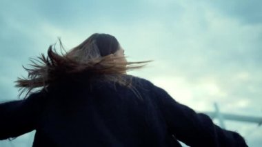 Şehir sokağında dönen bir kız. Yakından gülümseyen kadın el kaldırıyor.