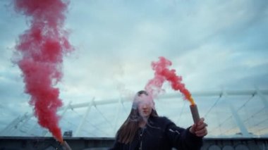 Şehir caddesinde elinde sis bombalarıyla duran kız. Hipster kameraya poz veriyor
