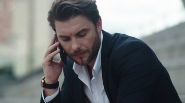 Stresli iş adamı caddede akıllı telefondan konuşuyor.