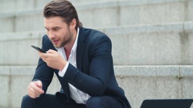 İşadamı akıllı telefondan sesli mesaj kaydediyor. Cep telefonu kullanan yönetici