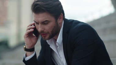İş adamı sokakta akıllı telefondan konuşuyor. Dışarıda cep telefonu kullanan bir adam.
