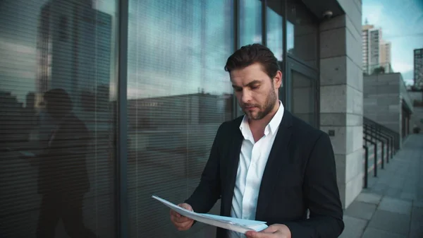 Businessman with documents walking near city building. Man reading documents — Stock Photo, Image