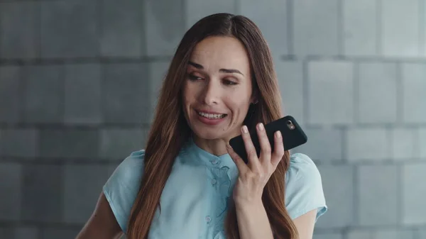 Mujer de negocios sonriente grabando mensaje de voz en un teléfono inteligente en la ciudad — Foto de Stock