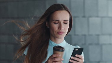 Şehirde akıllı telefon kullanan bir iş kadını. Müdür elinde kahveyle caddede dikiliyor.