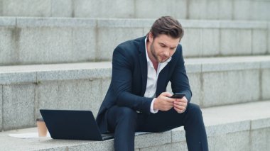 İş adamı sokakta cep telefonuyla mesaj atıyor. Akıllı telefon üzerinde çalışan bir profesyonel.