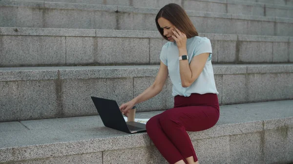 Geschäftsfrau liest gute Nachrichten am Laptop. Arbeitnehmerin spricht auf Smartphone — Stockfoto