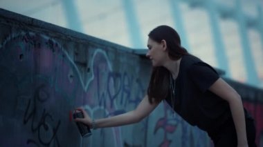 Şehir caddesinde grafiti yapan bir kız. Grafiti için sprey kullanan kadın.