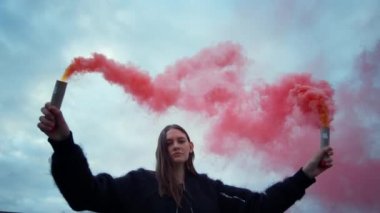 Kadın sis bombalarıyla protesto ediyor. Kız kameraya duman bombalarıyla poz veriyor