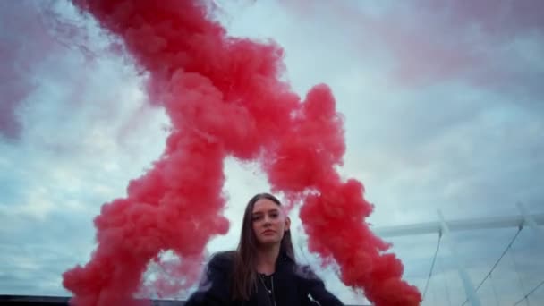 Flicka poserar framför kameran i färgglad rök. Attraktiv kvinna som håller rökbomber — Stockvideo