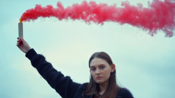 Tyttö pitelee savupommia kädessään katumielenosoituksessa. Savukranaattia käyttävä nainen — kuvapankkivideo