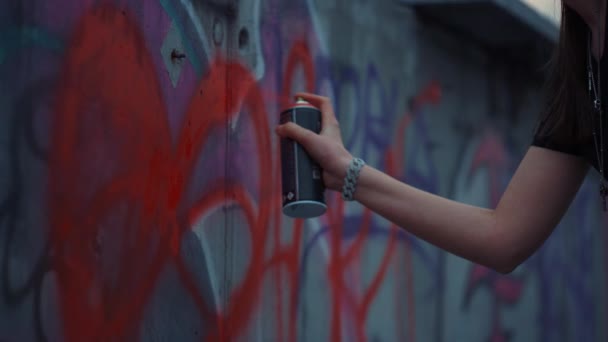 Kvinna handmålning graffiti på gatuväggen. Flicka ritar rött hjärta på byggnad — Stockvideo