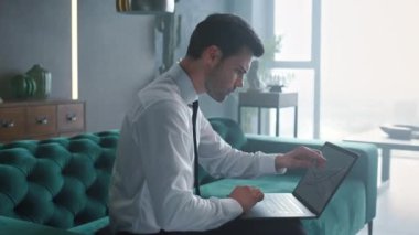 Ofiste dizüstü bilgisayarla çalışan bir iş adamı. Yönetici bilgisayardaki çizelgelere bakıyor