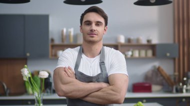 Gülümseyen aşçı ev mutfağına bakıyor. Yakışıklı adam el ele tutuşuyor..