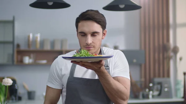Muotokuva hymyilevä kokki mies tilalla levy salaatti kotona keittiö . — kuvapankkivalokuva