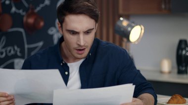 Merkez büroda belgeleri okuyan odaklanmış bir işadamı. Gülümseyen adam verileri analiz ediyor