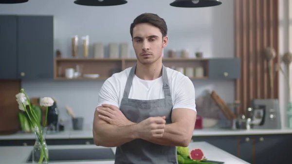 Poważny kucharz, mężczyzna patrzący na kamerę w kuchni. Mężczyzna przecinający ręce w środku. — Zdjęcie stockowe