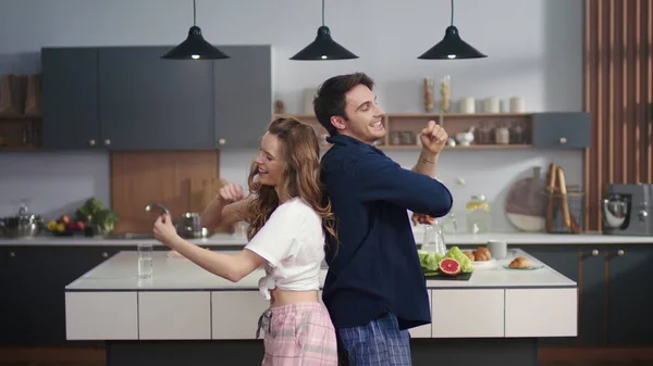 Pareja feliz bailando en la cocina de casa. Amigos emocionados divirtiéndose . —  Fotos de Stock