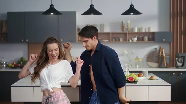 Pareja riéndose haciendo pijamas en la cocina. Hombre y mujer bailando juntos —  Fotos de Stock