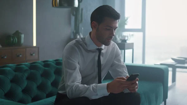 Serious business man browsing internet on mobile phone at remote workplace.