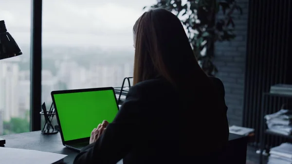 Young businesswoman using laptop with green screen for video call at home office