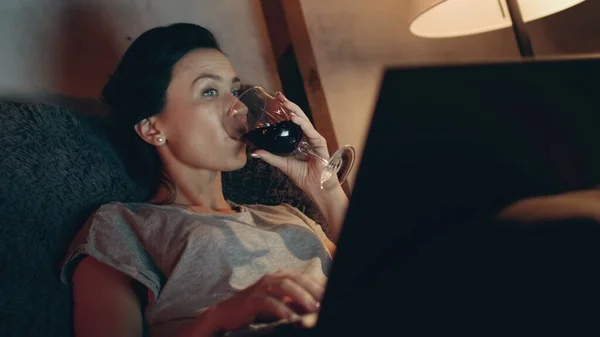Kobieta pijąca czerwone wino z laptopem. Dziewczyna surfing internet na komputerze. — Zdjęcie stockowe