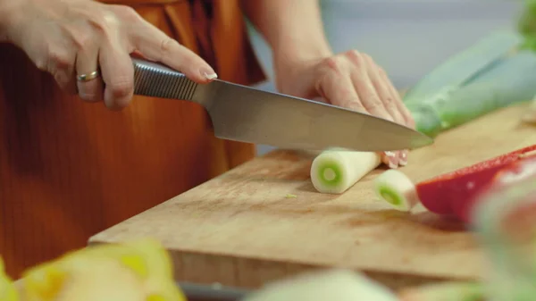 Mãos femininas cortando alho-porro verde. Menina preparando prato vegetariano saudável . — Fotografia de Stock