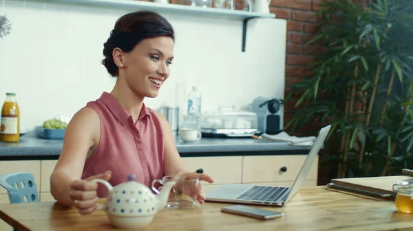 Kvinnan häller te i koppen under videosamtal. Flicka med bärbar dator för videochatt. — Stockfoto