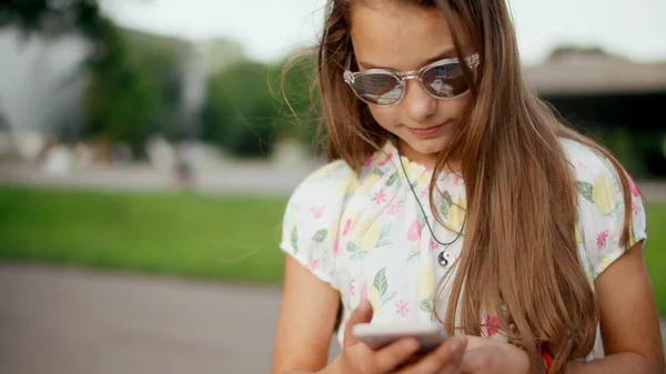 Χαμογελώντας έφηβος κορίτσι surfing internet στο κινητό τηλέφωνο στο πάρκο του καλοκαιριού. — Φωτογραφία Αρχείου