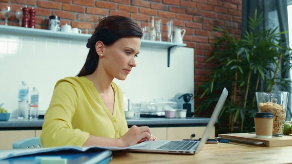 Exitosa empresaria que usa laptop en la cocina. Mujer recibiendo buen mensaje — Foto de Stock