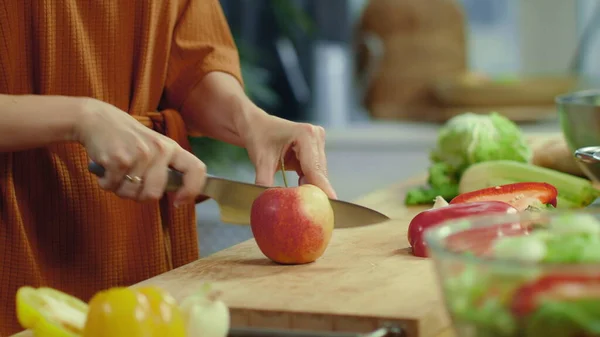 Mãos de mulher cortando maçã vermelha na cozinha. Dona de casa cozinhar salada de legumes . — Fotografia de Stock