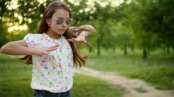 戴着太阳镜的小女孩在外面走来走去真有趣。可爱的少女在公园里跳说唱 — 图库照片