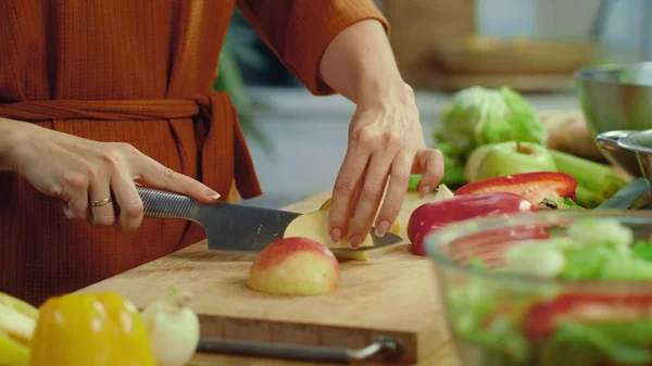 Mãos de mulher cortando maçã vermelha na mesa da cozinha. Menina degustação de maçã fatiada em casa — Fotografia de Stock