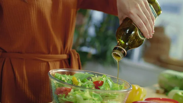 Le mani di donna versano l'olio d'oliva in ciotola di mescolanza. Bruna rendendo insalata di verdure. — Foto Stock