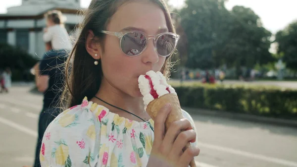 Pretty girl eating ice cream cone. Relaxed teen girl walking in amusement park