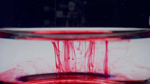 Γυάλινα αντικείμενα εργαστηρίου με δείγμα αίματος. Ερυθρό χημικό αντιδραστήριο που ρέει στο νερό — Φωτογραφία Αρχείου